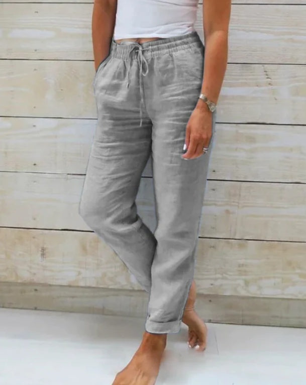 Person wearing light gray pants against a wooden background