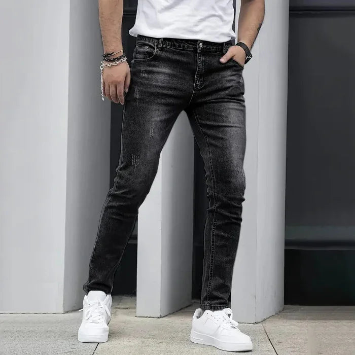 Person wearing black jeans and white sneakers against a neutral background
