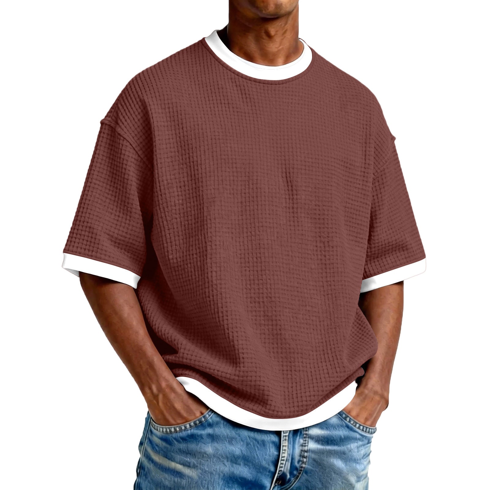 Man wearing a maroon textured t-shirt with white trim and blue jeans on a white background