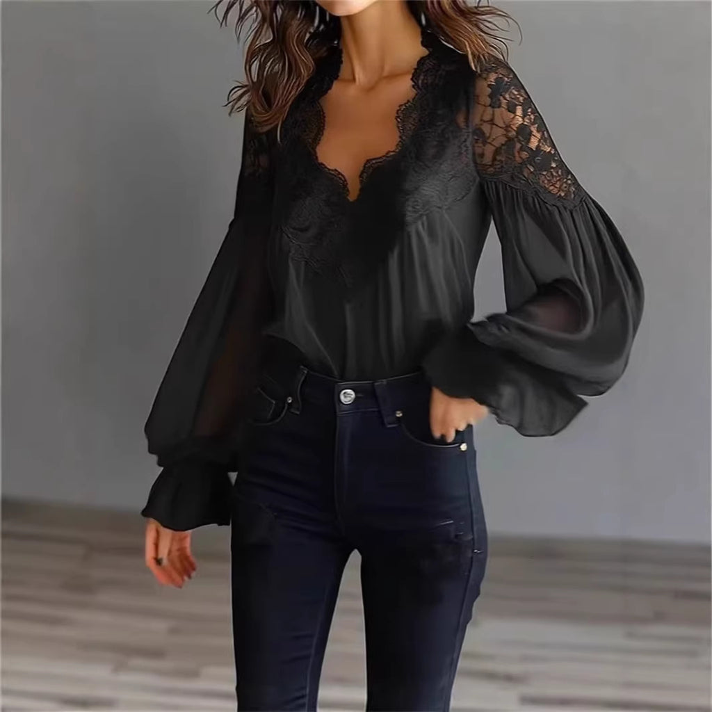 Person wearing a black blouse with lace sleeves and dark jeans against a neutral background