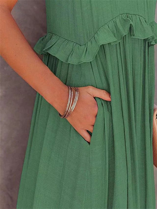Green dress with ruffled details worn by a person, with a neutral background
