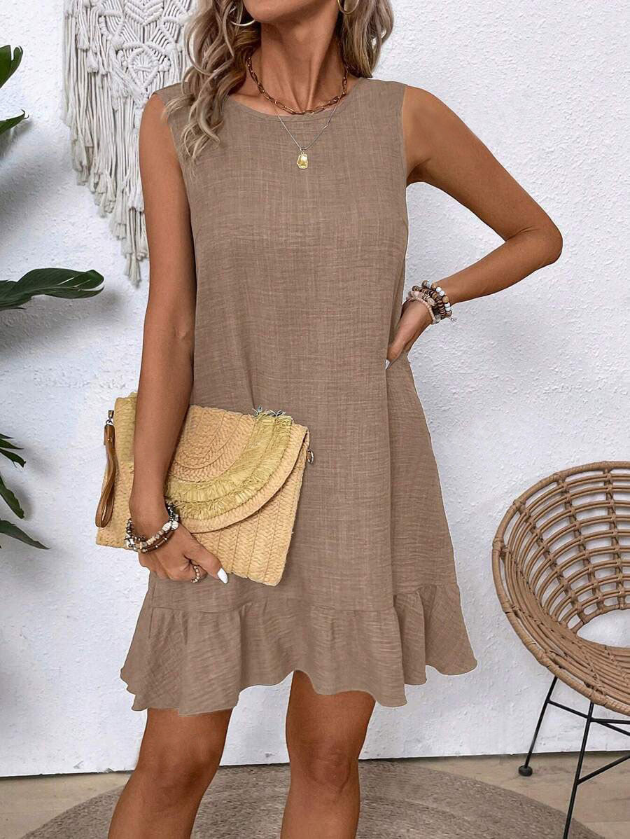 Woman wearing a beige dress holding a yellow clutch in an outdoor setting.