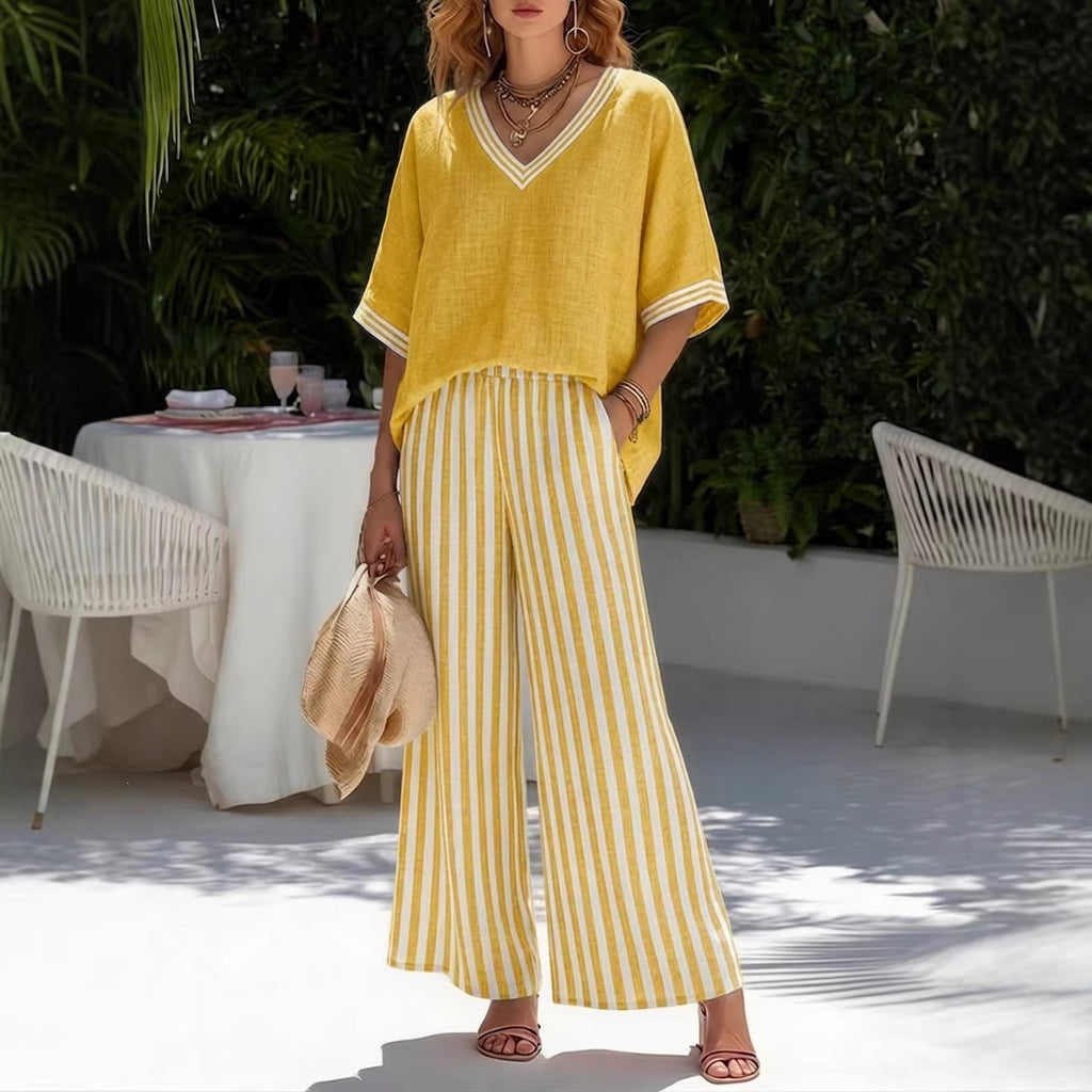 Woman in yellow outfit standing outdoors with a table and chairs in the background