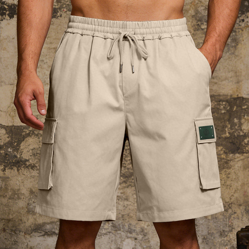 Beige cargo shorts worn by a person against a textured wall background