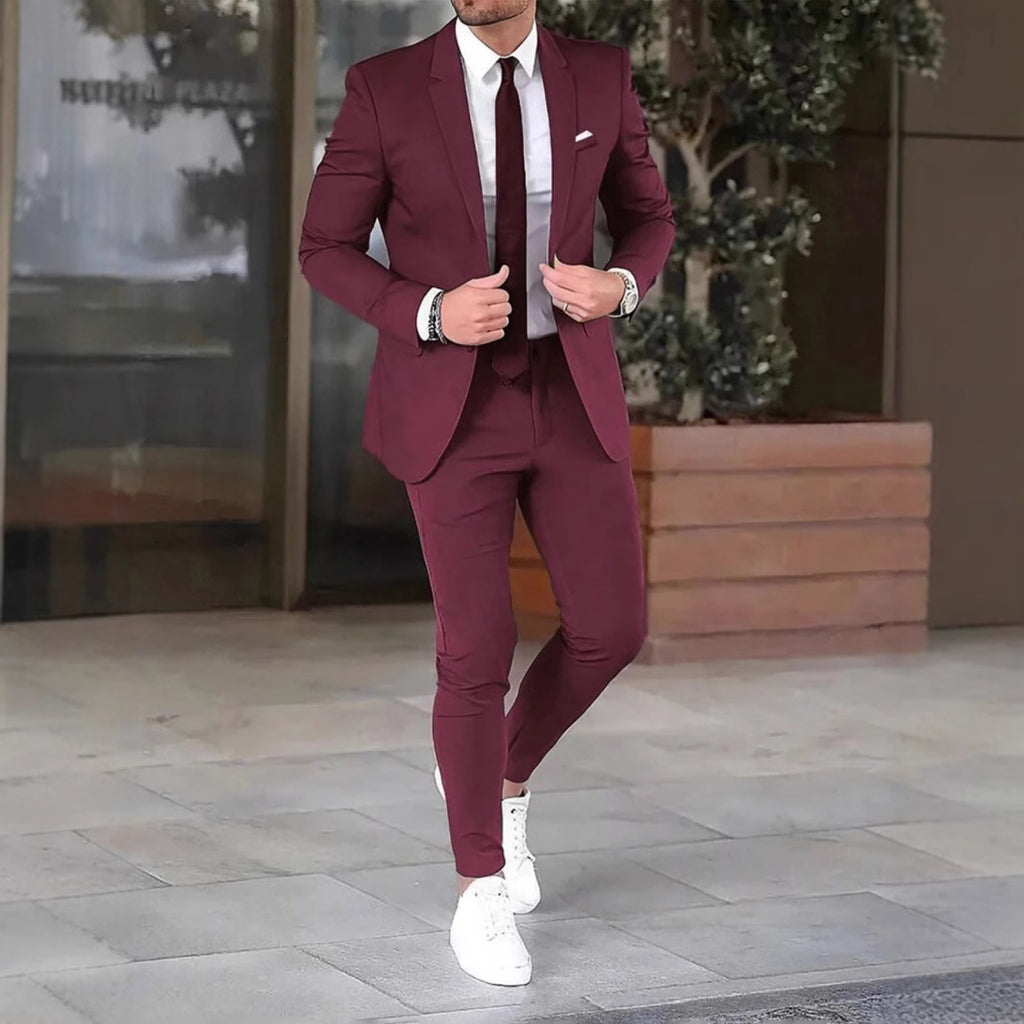 Man wearing a burgundy suit with white shoes on a city street.