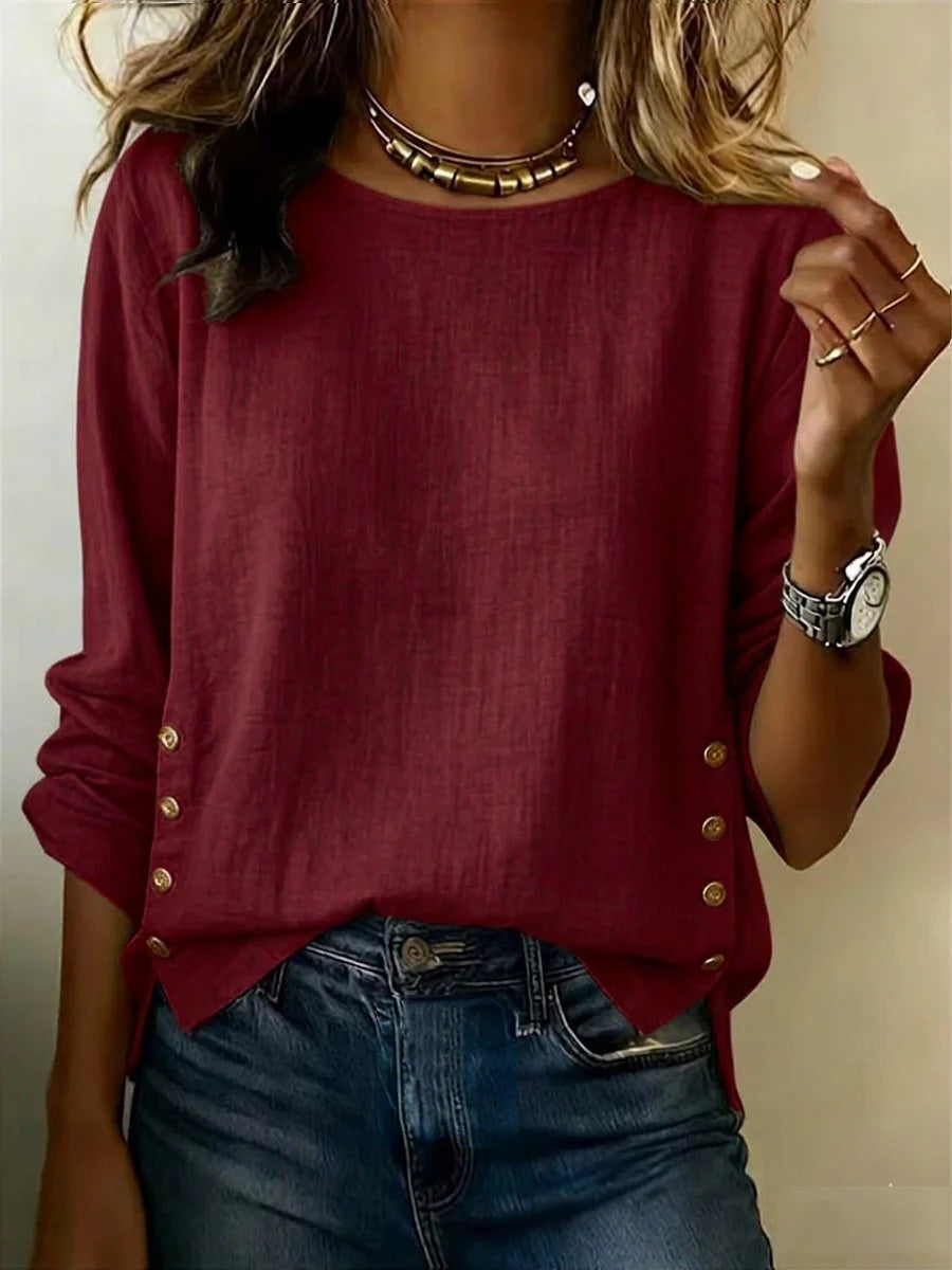 Red long-sleeve top with button details worn by a person, against a neutral background