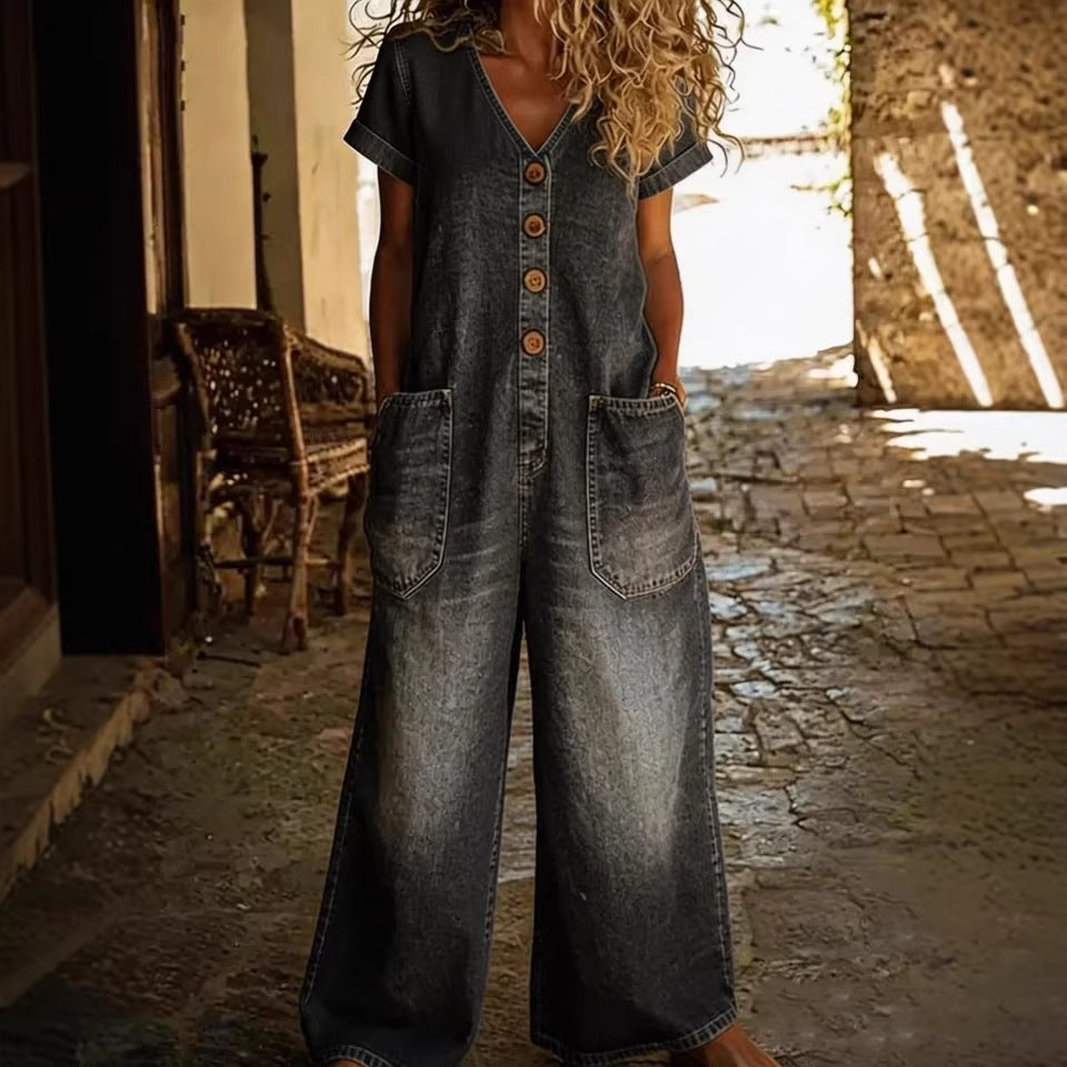 Person wearing a denim jumpsuit standing in a sunlit alleyway.