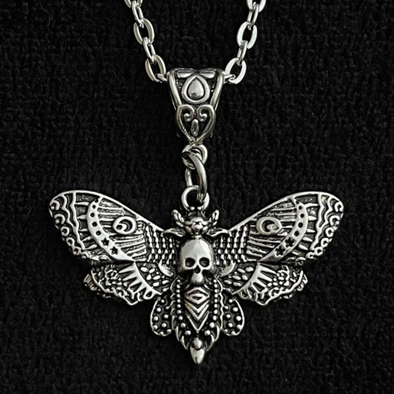 Silver moth-shaped pendant with skull design on a black background