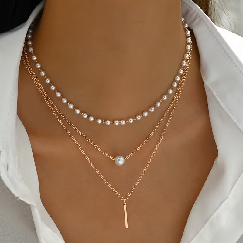 Two pearl necklaces layered on a person's neck with a white shirt background