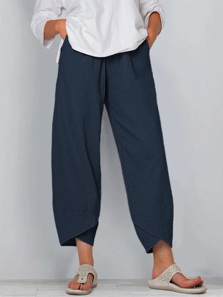 Person wearing navy wide-leg pants and a white shirt on a plain background