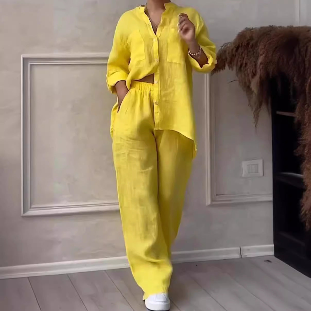 Person wearing a bright yellow outfit standing in a room with a neutral wall and wooden floor.