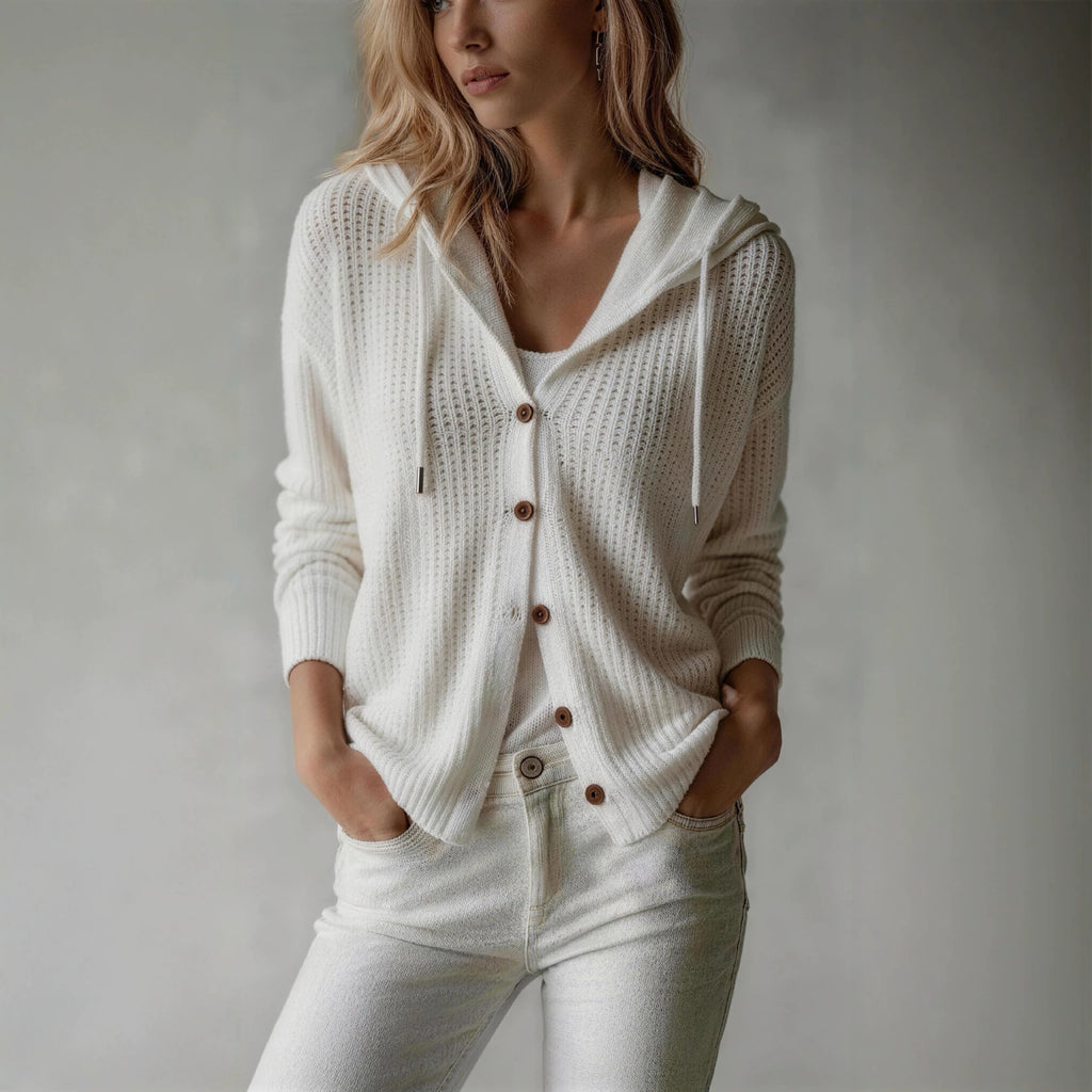 Woman wearing a white knit cardigan with brown buttons on a plain background