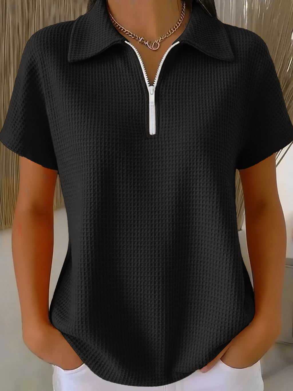 Black textured short-sleeve shirt with a zipper on a mannequin against a neutral background
