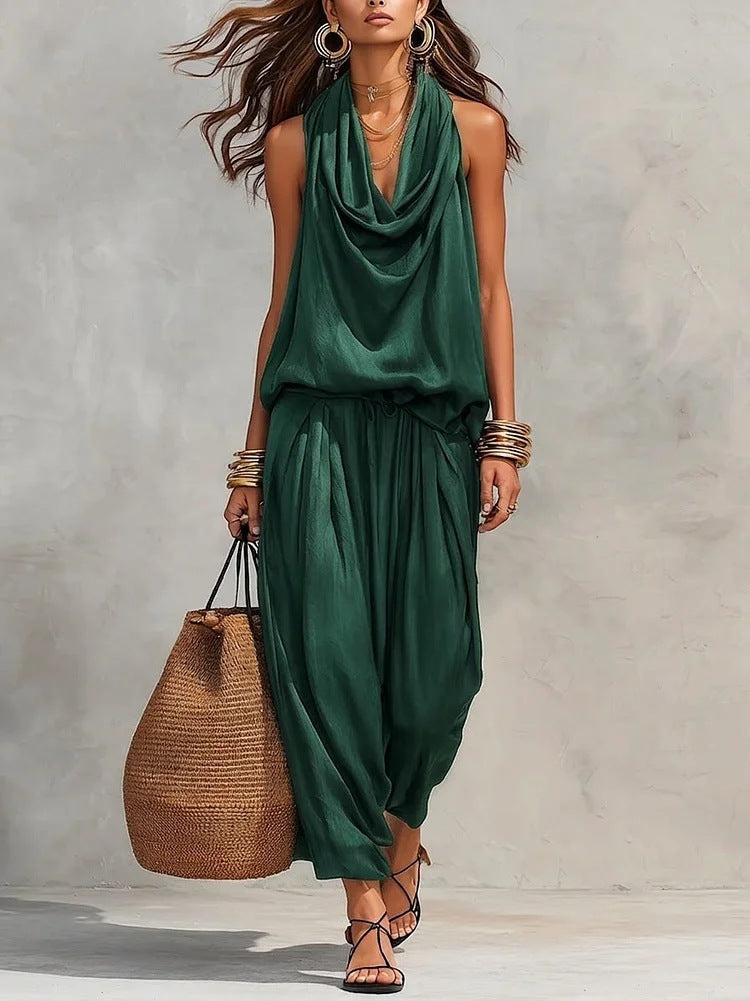 Woman wearing a green dress holding a woven bag against a plain background