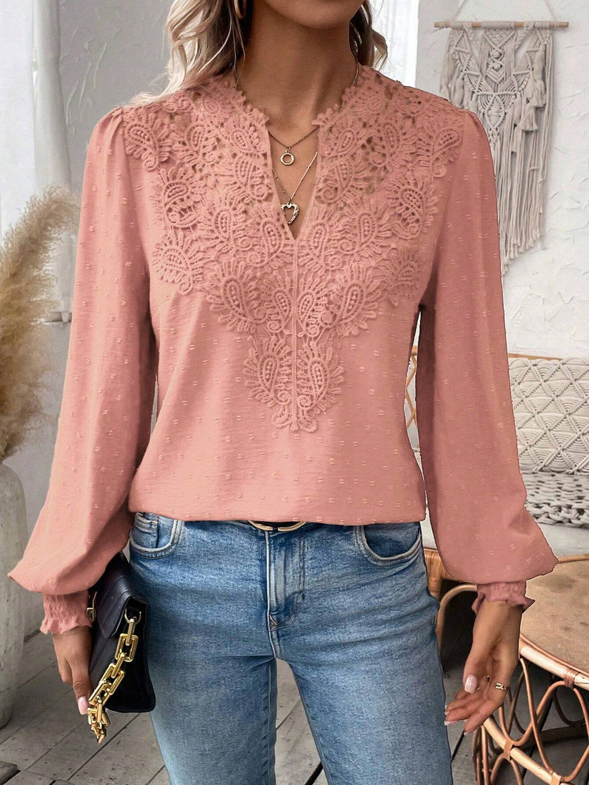 Person wearing a pink lace top and blue jeans indoors.