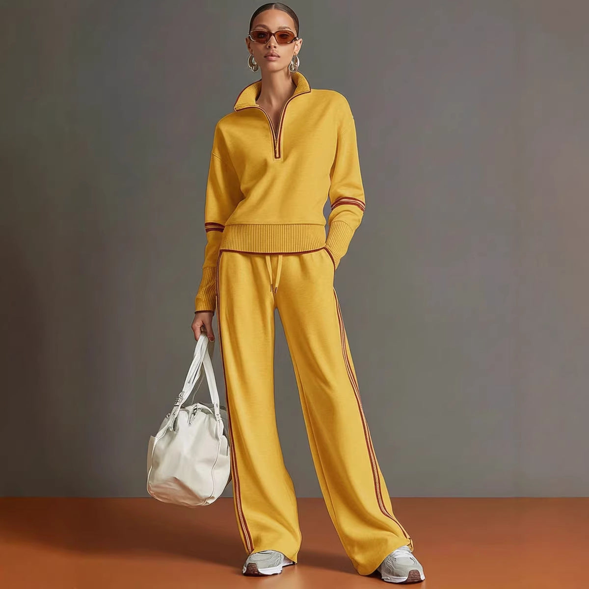 Woman wearing a yellow tracksuit holding a white bag against a gray background