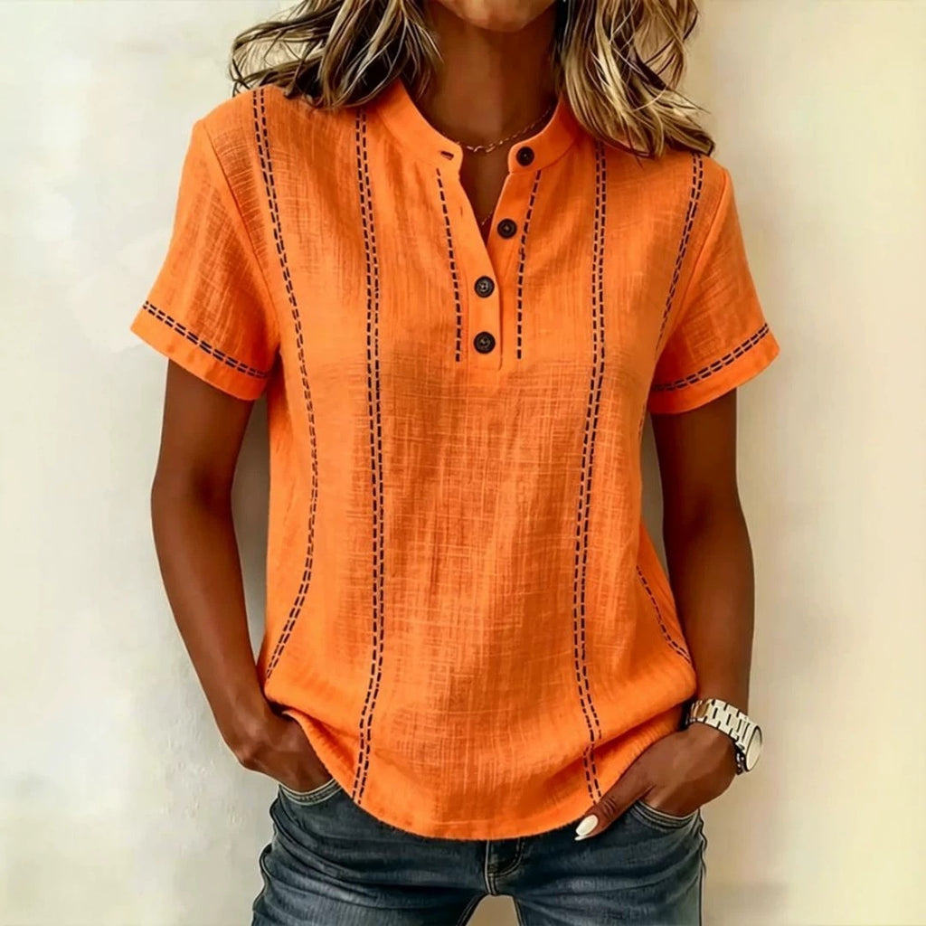 Person wearing an orange short-sleeve shirt with black stitching on a plain background
