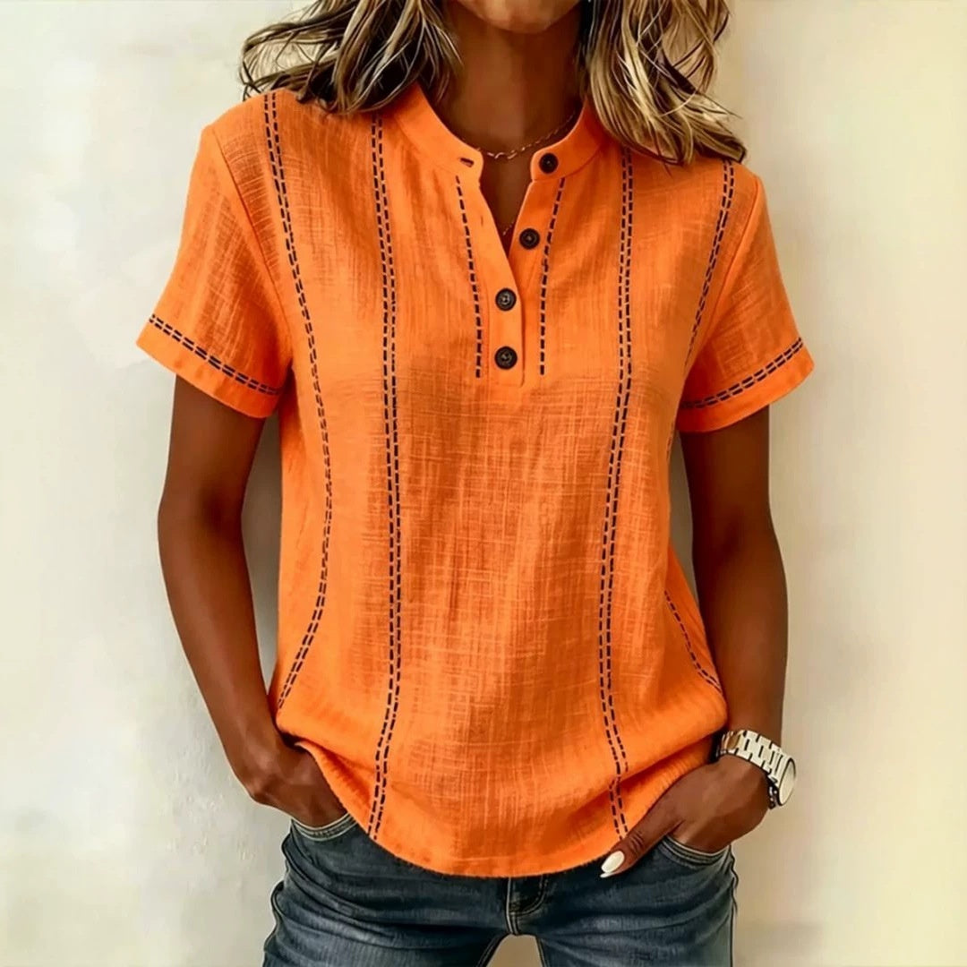 Person wearing an orange short-sleeve shirt with black stitching on a plain background