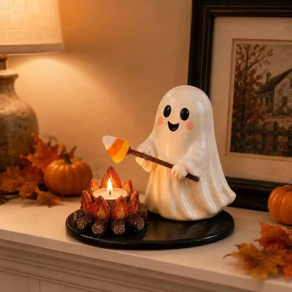 A cute white ghost figurine holding a candy corn wand, standing next to a small lit candle holder on a black base, styled on a mantel with autumn leaves, pumpkins, and a lamp.