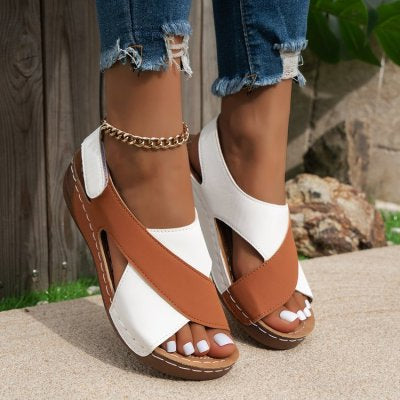 Brown and white sandals worn with ripped jeans on a blurred outdoor background