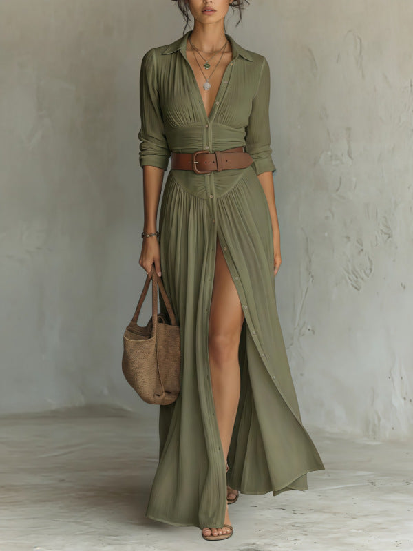 Woman wearing a long olive green dress with a slit, holding a brown bag against a plain background.