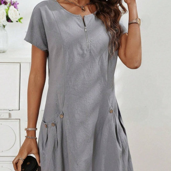 Woman wearing a gray dress with buttons on a white background
