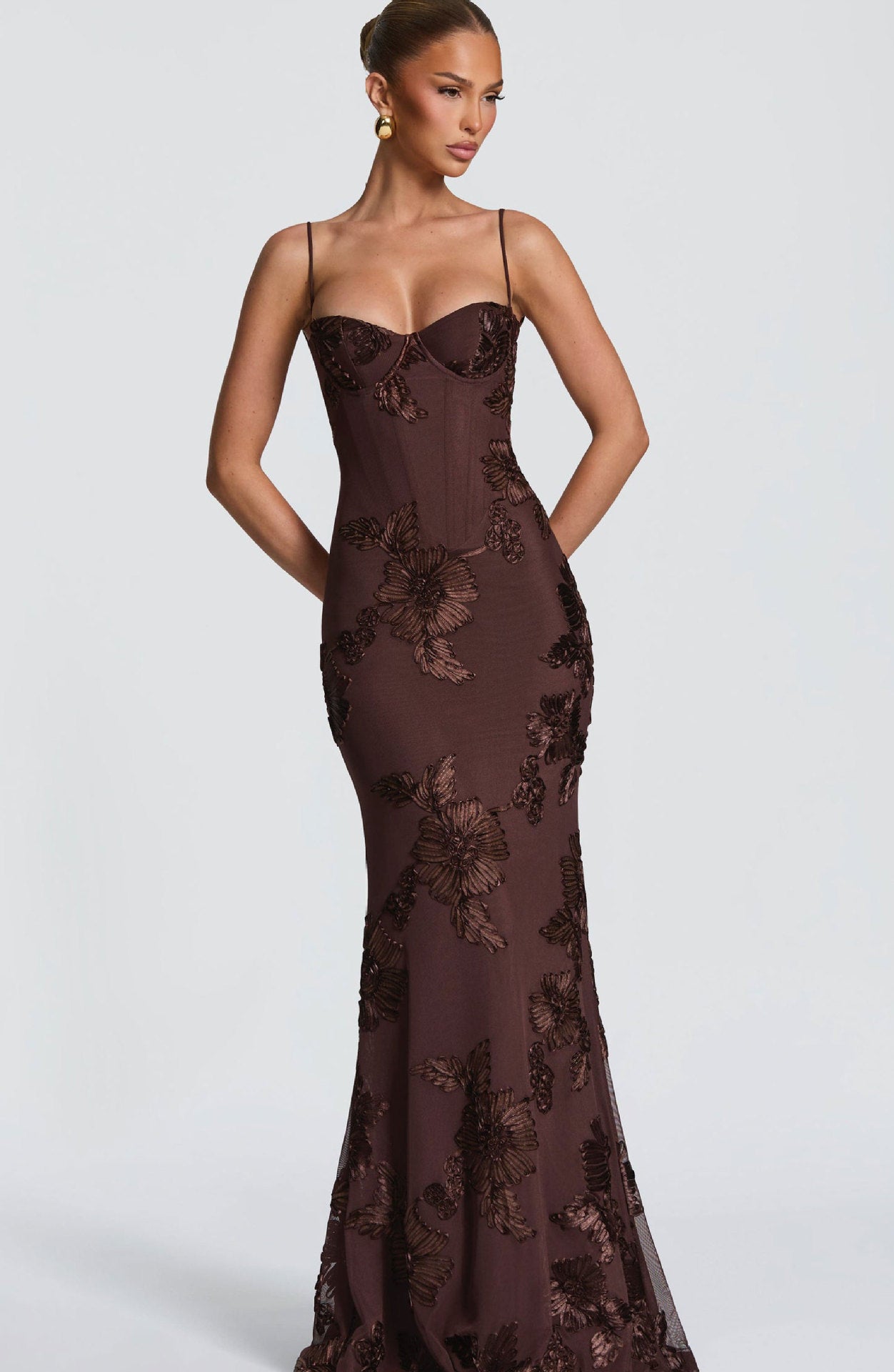 Brown evening gown with floral lace details on a white background
