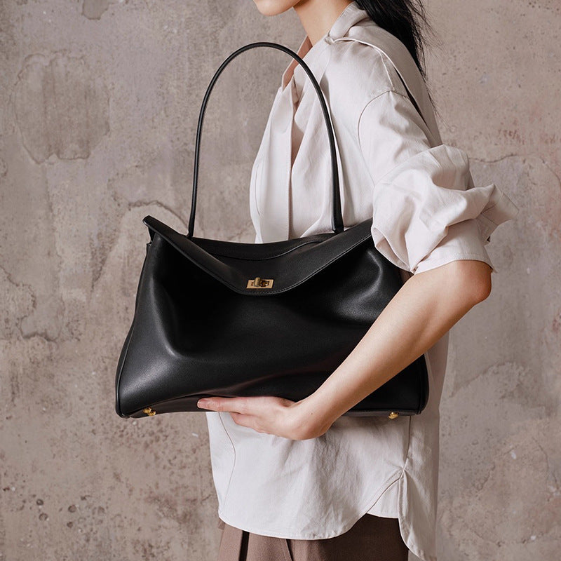 Person holding a black handbag against a textured wall