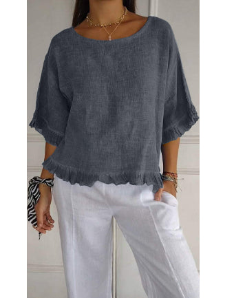 Person wearing a blue linen top and white pants against a neutral background