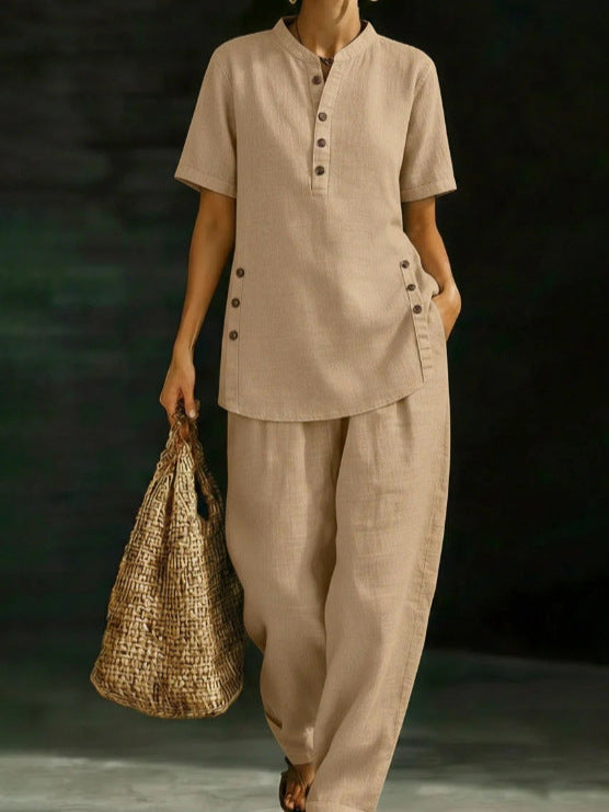 Person wearing a beige outfit holding a woven bag against a dark background