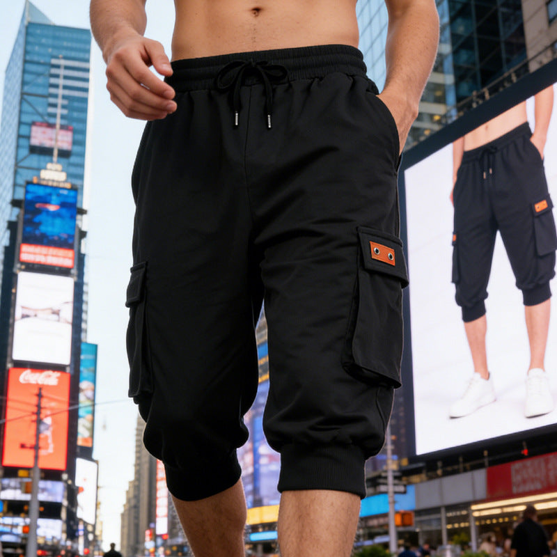Person wearing black cargo shorts in an urban setting with billboards in the background