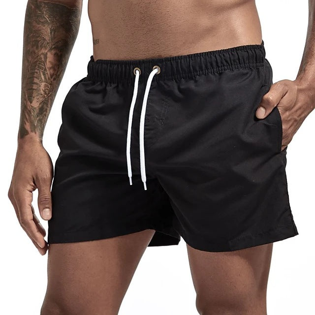 Black swim shorts with a white drawstring on a white background