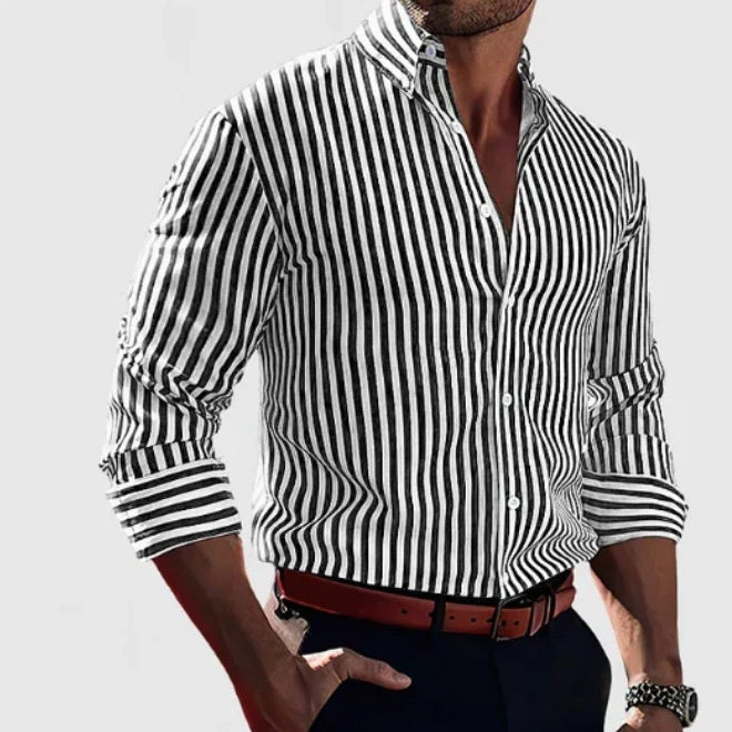 Man wearing a black and white striped shirt with rolled-up sleeves on a light gray background