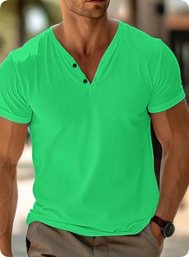 Man wearing a bright green V-neck t-shirt with a blurred background