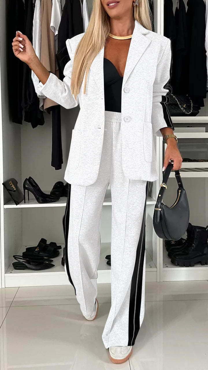 Woman in a white suit with black stripes standing in a closet.