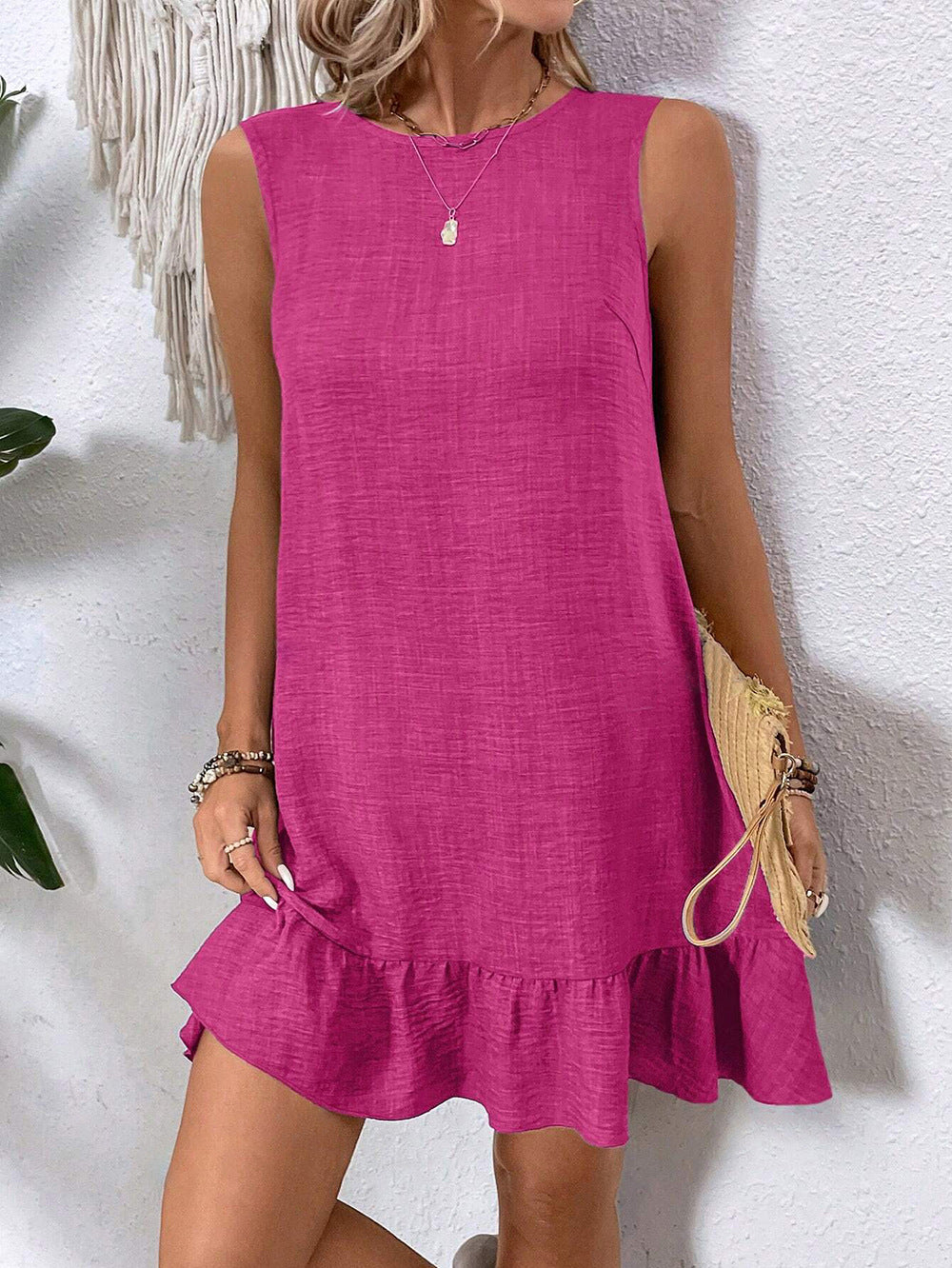 Woman wearing a pink dress against a textured white wall.