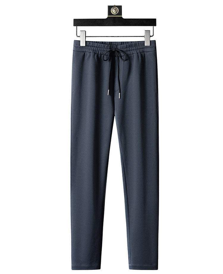 Men’s navy blue jogger pants with drawstring waist and textured fabric, hanging on hanger