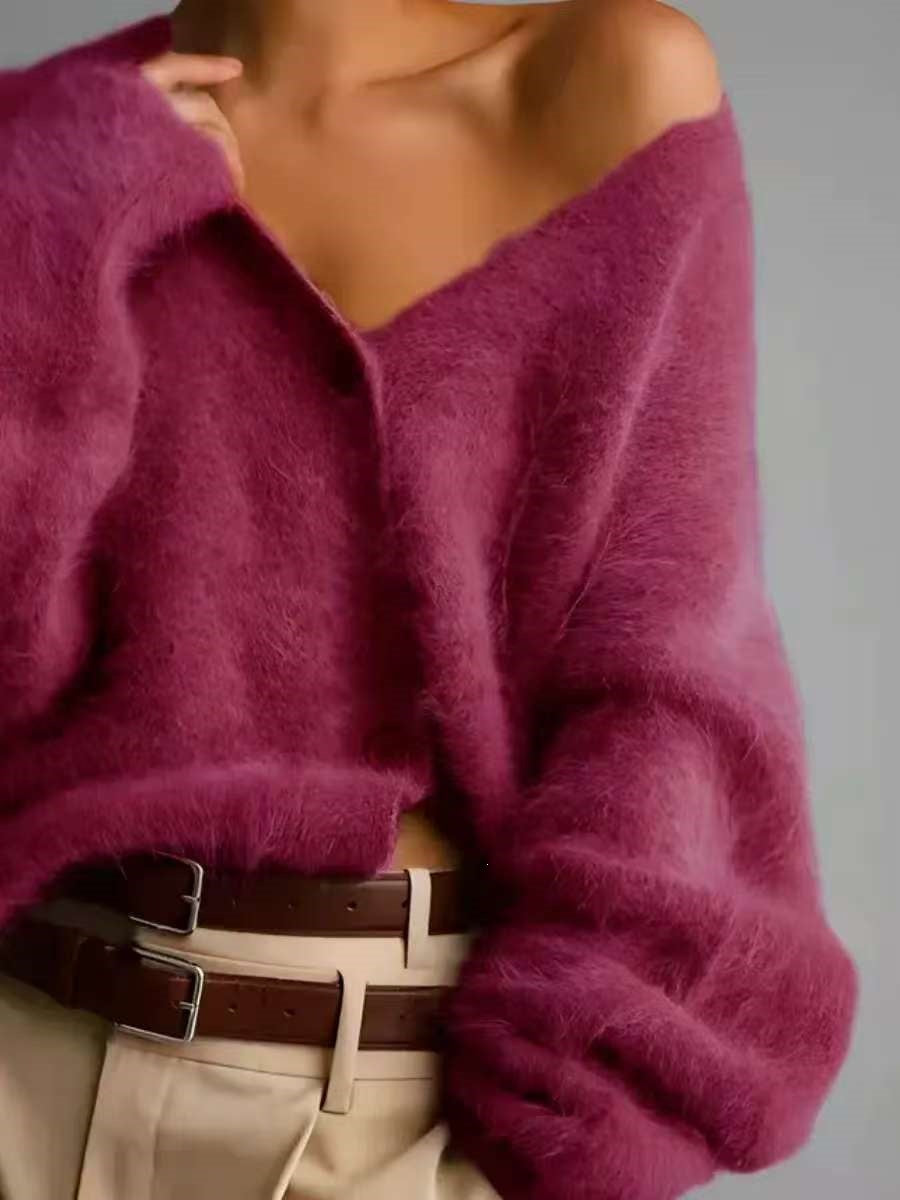 Close-up of a person wearing a magenta sweater with a neutral background
