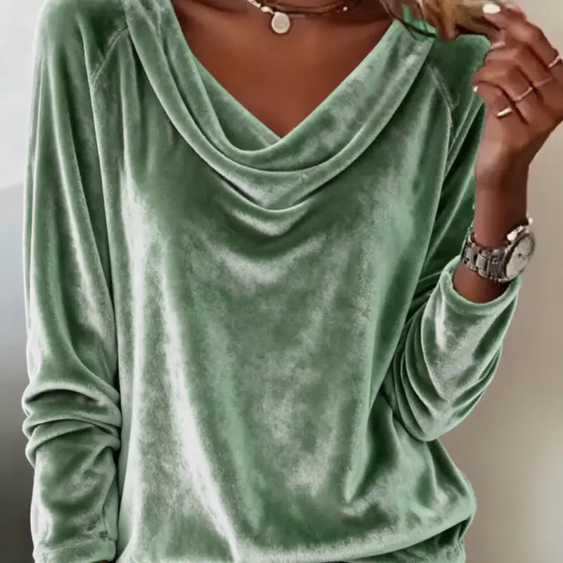 Green velvet long-sleeve top worn by a person, with a neutral background