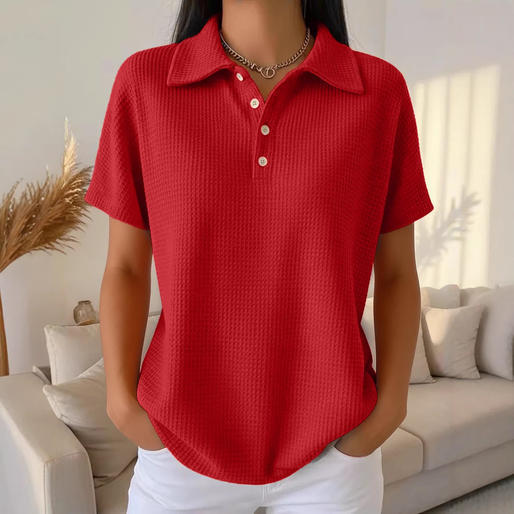 Person wearing a red textured polo shirt in a living room setting