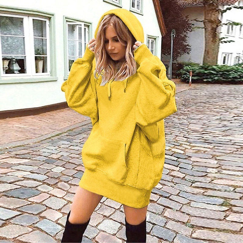 Person wearing a bright yellow oversized hoodie on a cobblestone street.