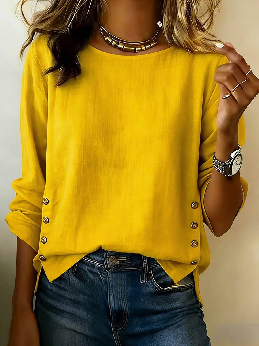 Person wearing a yellow long-sleeve top with button details and blue jeans.