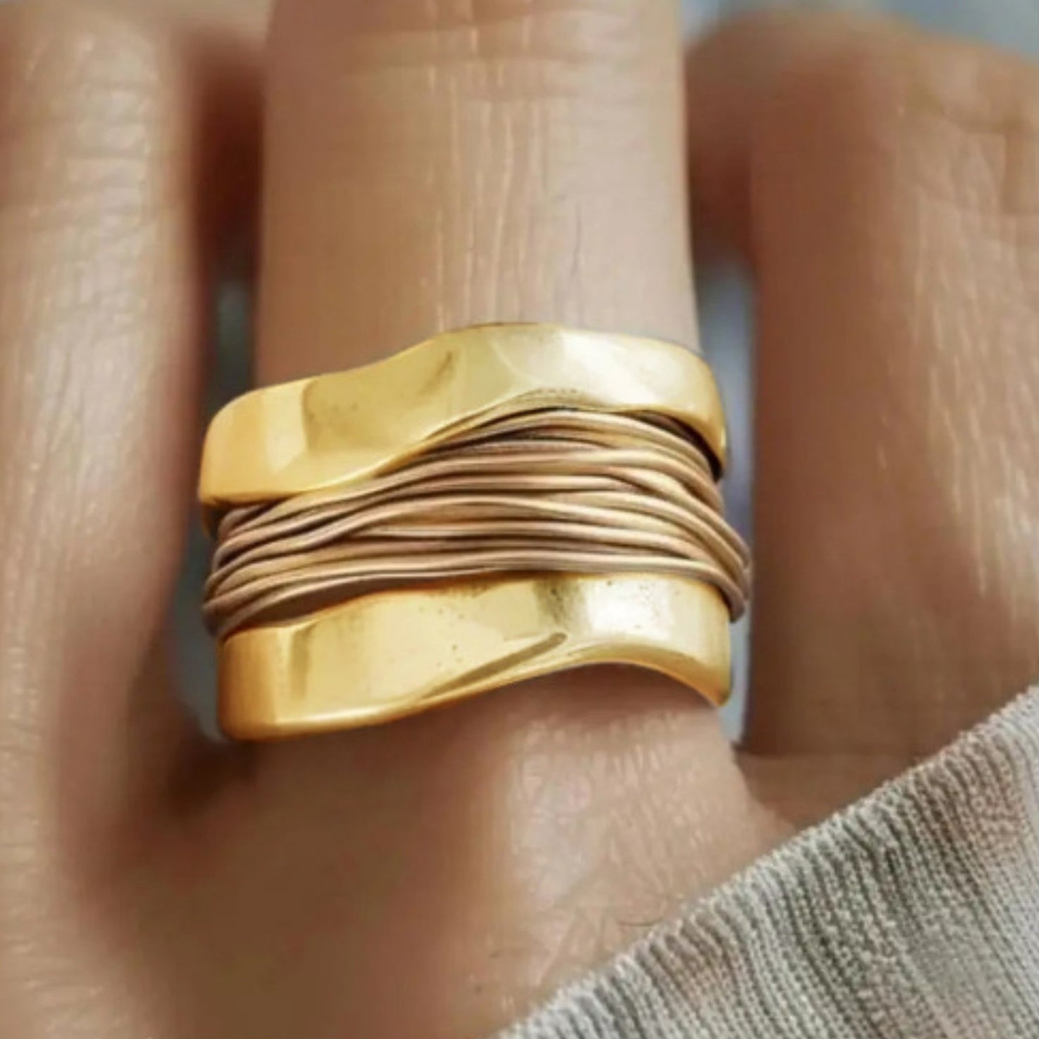 Gold ring with textured design worn on a finger