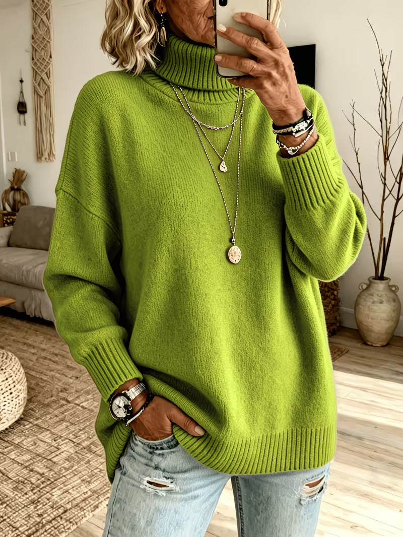 A woman takes a mirror selfie wearing a bright lime green ribbed turtleneck sweater and light-wash distressed jeans in a cozy living room setting.