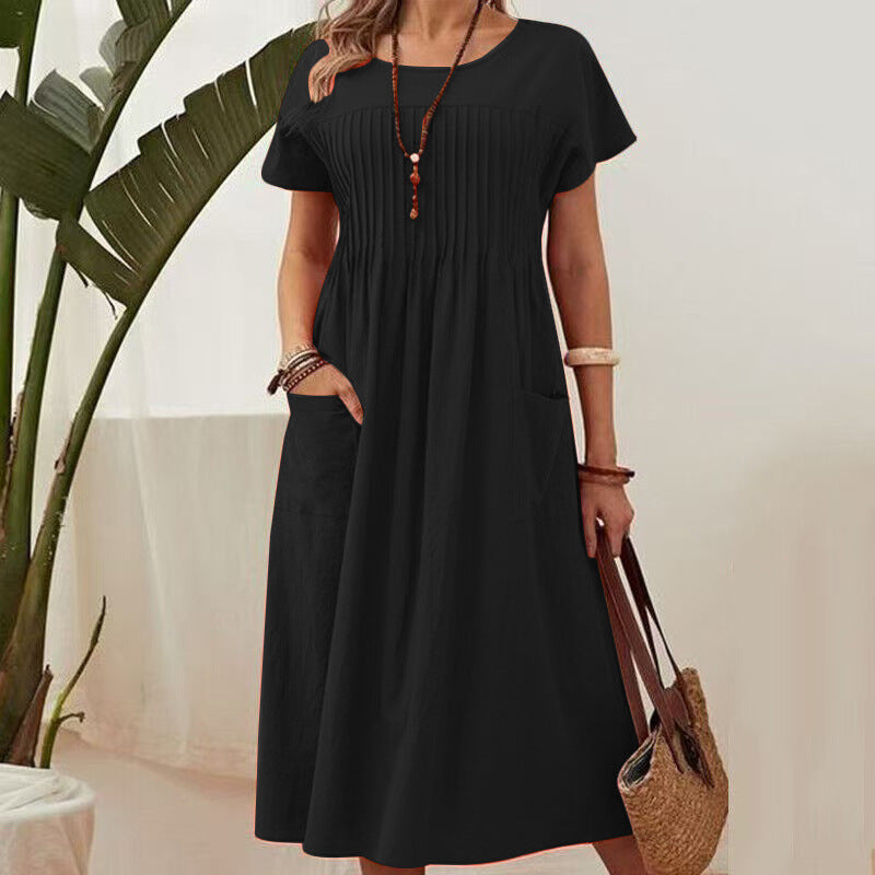 Person wearing a black dress holding a straw bag indoors with a plant in the background