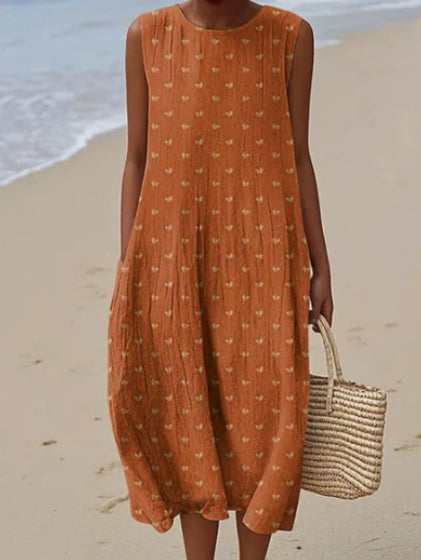Person wearing an orange dress with a subtle pattern on a beach.