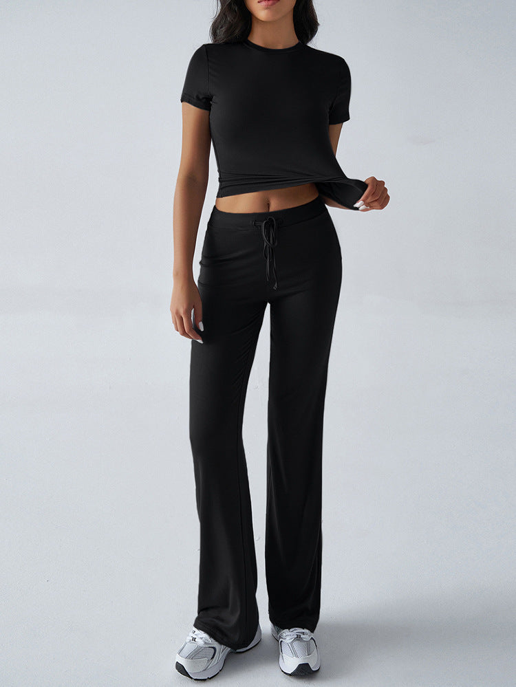 Person wearing a black outfit with a crop top and pants on a white background