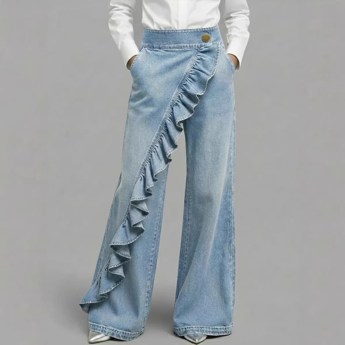 Light blue denim jeans with ruffled details on a gray background