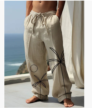 Person wearing beige pants with black spider designs by the ocean.