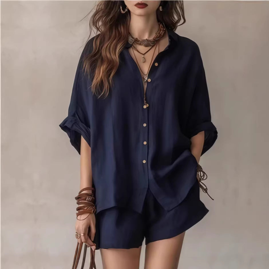 Person wearing a navy blue shirt and shorts with accessories on a plain background